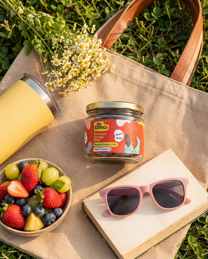 Pro Bites Co Munakka Badam Oats jar in a flat lay with fresh fruit, sunglasses and a canvas tote